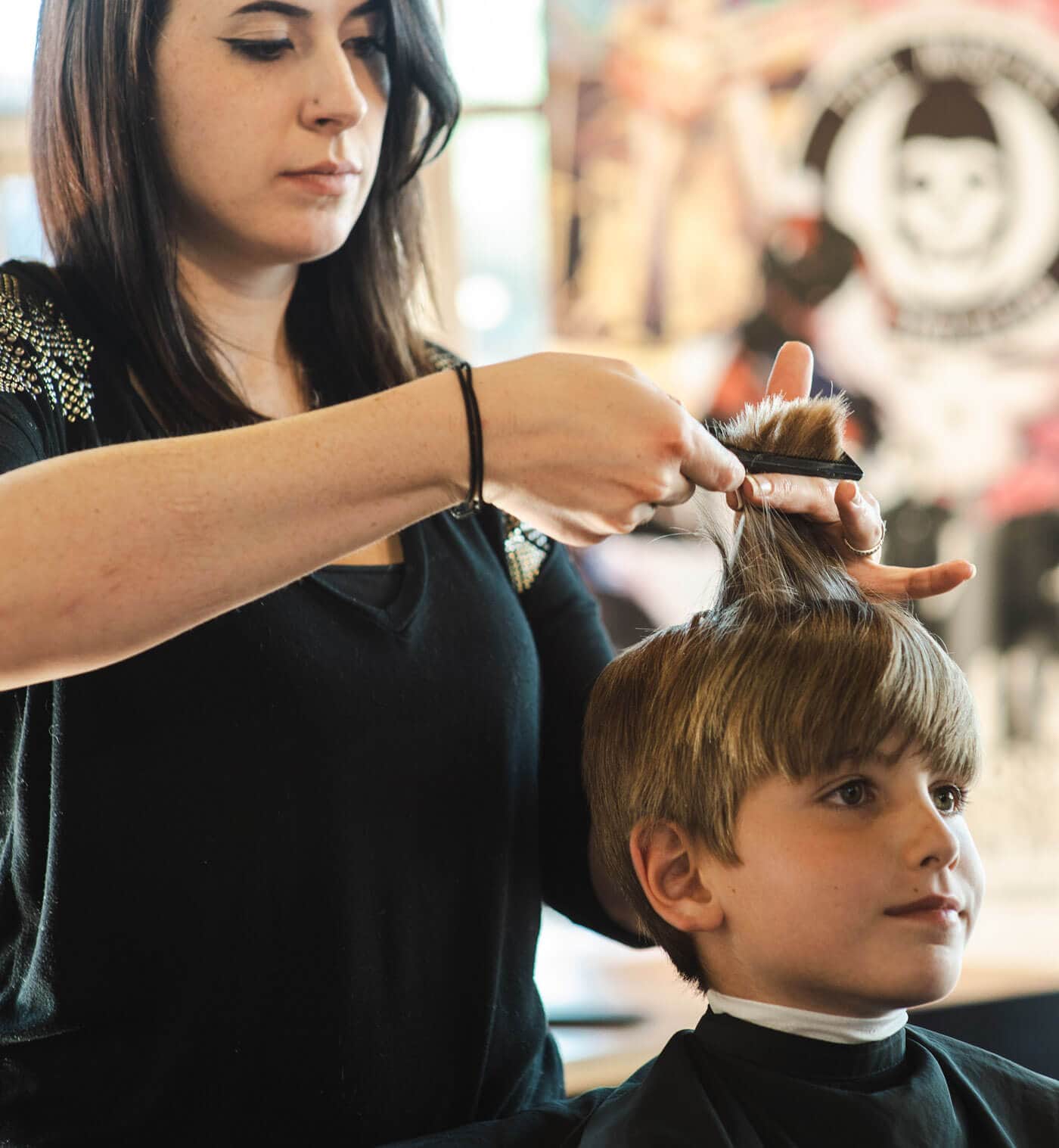 A young boy getting his haircut in a salon by a hairstylist