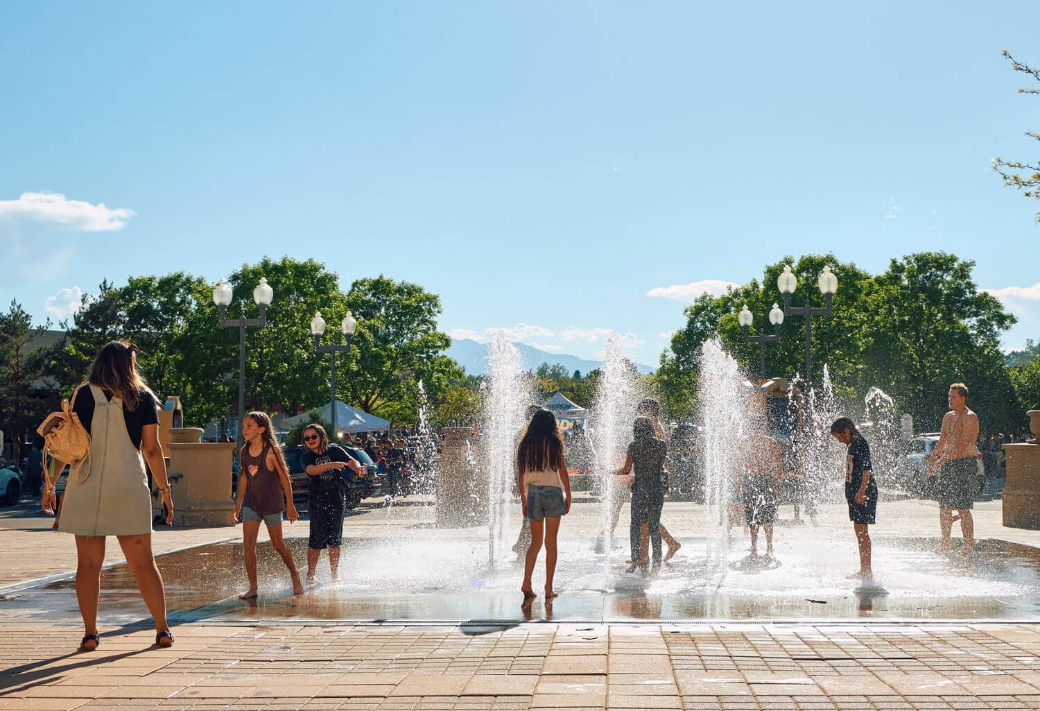 Kids playing in an outdoor fountain under the sun