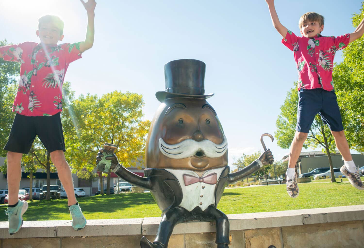 Two kids jumping off a bench next to a character statue