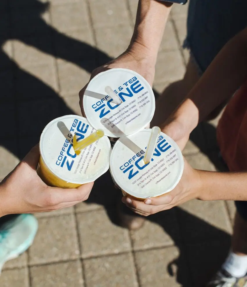 Three guests holding Coffee and Tea Zone branded cups with straws